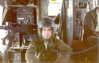 The author in gunner's position. Behind is the electronics rack. Today all those boxes are in the panel but the rack is filled with computers. You can just see the pilot's arm and the crew chief on the right. The seats were improvised and gave no protection at all in a crash. The crew chief usually broke his back on the controls closet and the gunner landed wherever he landed.