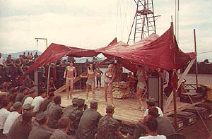 This was a party organized by the squadron. We hired a band and dancers and stopped the war for an afternoon. We built the stage on the flight line. Notice helos and the Marble Mountains in the background. The guys in the front row were as close to the stage as they could get without actually being on it. The band and 3 of the 4 dancers were Australian. The other dancer was from Liverpool and all the guys thought that would give me an edge. Not a chance. Her boyfriend was a 'bird' (full) Colonel and I didn't even come close even though I was making more money than he was. He had more clout. 